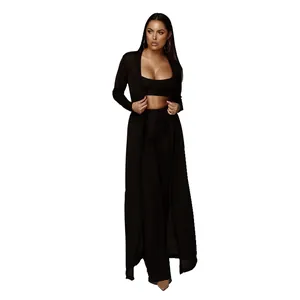Femme portant un ensemble en maille noir 3 pièces avec long gilet, haut court et pantalon