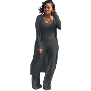Stylish woman wearing a dark grey three-piece ribbed knit outfit with cardigan and pants