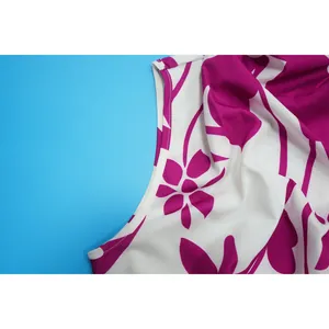 Detailed macro view of the neckline stitching and vibrant purple floral print on white fabric.