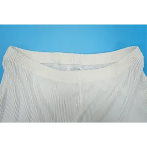Detailed view of the elastic waistband and fine pleated texture on white casual pants.