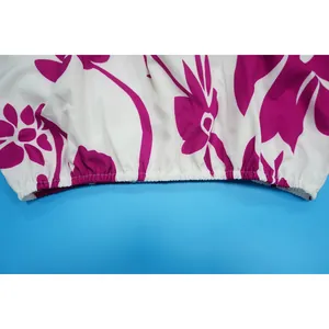 Close-up detail of elasticized hem with vibrant purple floral print on white fabric.