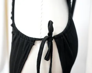 Detailed close-up view of a black ribbed dress featuring a functional shoulder tie knot.