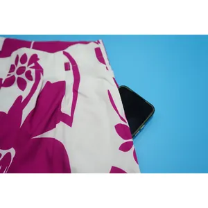 Detailed view of the functional side pocket on floral print pants with a phone inside