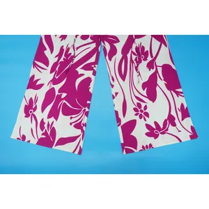 Close-up detail of women's wide-leg pants featuring a bold magenta floral print