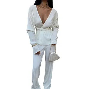 Detailed view of stylish white pleated two-piece set with deep V-neck and waist tie
