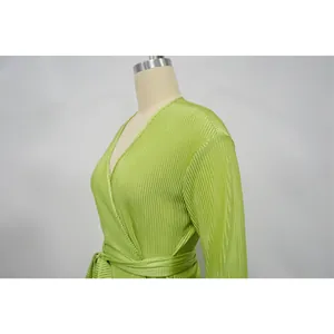 Close-up of a lime green pleated long-sleeve wrap dress detailing the texture and V-neck.