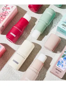 Close-up of FORMBO solid perfume balms in various colors with floral packaging detail