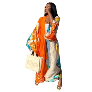 Full-length view of a woman wearing a vibrant orange printed loose kimono cardigan.