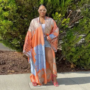 Detailed outdoor fashion shot of a vibrant orange floral print kimono cardigan with loose fit