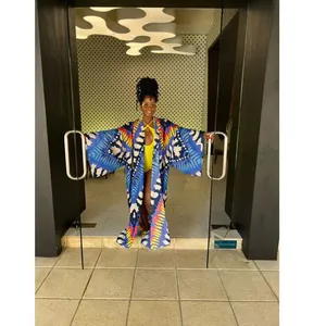 Fashionable model posing in a vibrant printed long kimono cover-up at a modern entrance