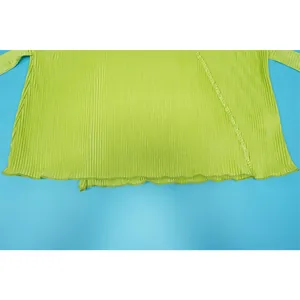 Close-up of lime green pleated fabric texture and hem detail on a casual long sleeve top.