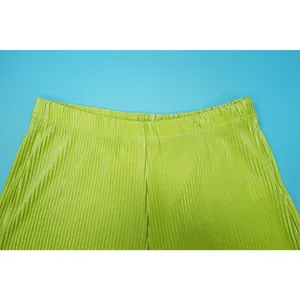 Detailed view of lime green pleated trousers showing the elastic waistband and texture