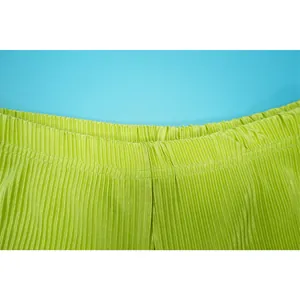 Close-up detail of elasticated waistband showing fine pleat texture on lime green pants.