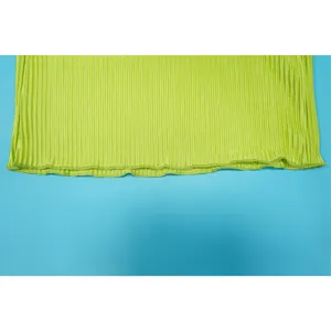 Close-up detail showing lime green pleated fabric texture and wavy stitched hemline