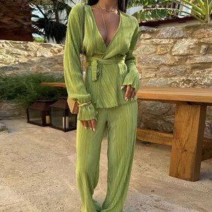 Detailed view of the vibrant green pleated long-sleeve top and wide-leg trousers set