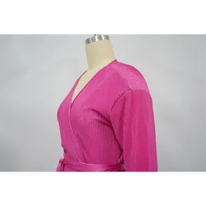 Close-up detail of fuchsia pleated fabric on a long sleeve dress with stylish waist tie