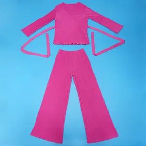 Flat lay of a pink pleated two-piece set with wrap top and wide-leg pants on blue background.