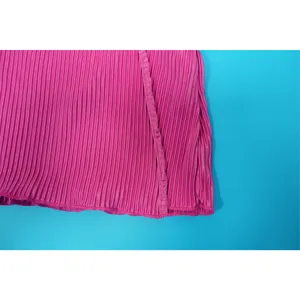 Close-up detail of pleated pink fabric texture and fine hem stitching on women's top