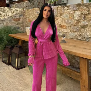 Outdoor lifestyle shot of a magenta pleated long-sleeved top and wide-leg pant set