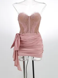 Detailed view of a pink ruched mini dress with a lace corset top and bow accent.