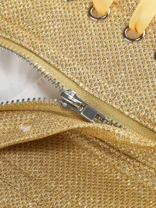 Detailed macro view of golden sequin dress with silver zipper and ribbon lacing