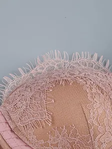 Detail view of the intricate pink floral lace and eyelash trim on a mesh evening dress
