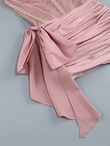 Detailed close-up of a pink mesh lace dress featuring a stylish side bow and ruching texture