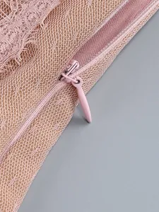 Macro view of high-quality hidden zipper detail on a pink sheer lace and mesh dress.
