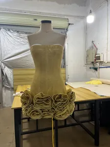 Detailed macro view of golden sequined strapless bodycon dress with 3D ruffled floral hem