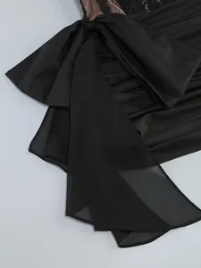 Close-up of elegant black mesh cocktail dress featuring a large bow and lace detail