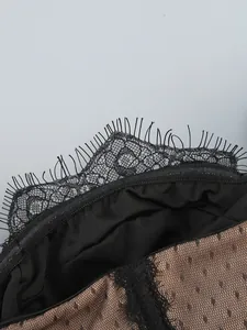 Macro detail of black eyelash lace trim and brown dotted mesh fabric on a sexy dress