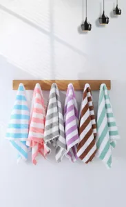 Six colorful striped coral fleece towels hanging on a wooden rack for home decor