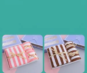Detailed view of luxury striped towel gift sets in pink and brown with elegant ribbons.