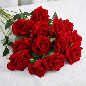 Detailed macro view of vibrant red velvet artificial roses on a white lace surface.