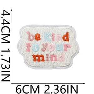 Gros plan de l'écusson brodé 'be kind to your mind' avec dimensions précises de 6 cm.
