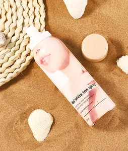 Dettaglio del flacone spray Idol White Tan sulla sabbia con conchiglie decorative
