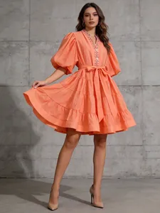 Vista detallada de un vestido naranja con cuello en V, mangas abullonadas y lazo