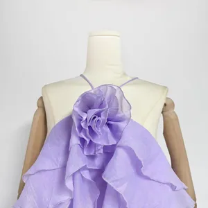 Close-up of elegant lavender dress featuring a large 3D fabric flower and ruffles.