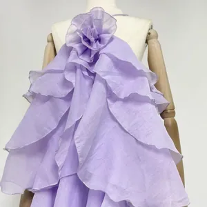 Detail of elegant lavender layered ruffle dress with 3D flower decoration at neck.