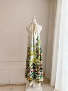 Detalle de vestido largo con estampado de jungla y un elegante lazo en el cuello atrás.
