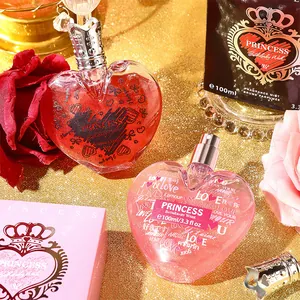 Two elegant heart-shaped perfume bottles with crown caps presented on a golden glitter backdrop