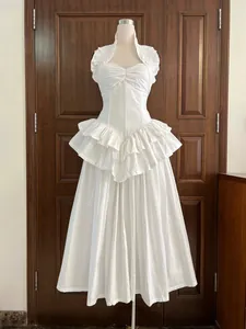 Detailed view of white pleated maxi dress with corset waist and tiered ruffle hem