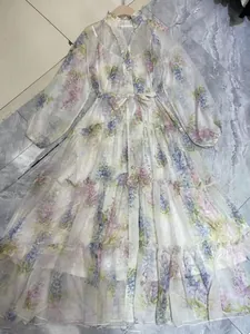 Close-up of floral print sheer dress with lantern sleeves and tiered ruffled skirt detail.