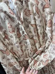 Close-up detail of a paisley print dress featuring front buttons and an adjustable waist tie