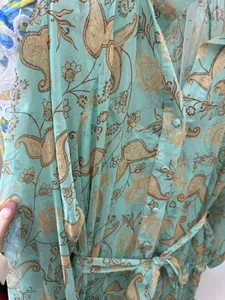 Close-up detail of turquoise paisley print chiffon dress featuring buttons and waist tie