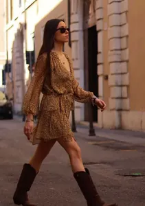 Woman in a leopard print V-neck lantern sleeve dress walking on a city street.