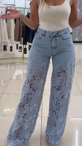 Détail d'un jean bleu clair à taille haute et jambes larges avec empiècement en dentelle.