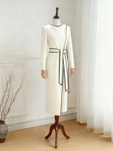 Vestido elegante crema de manga larga con ribete negro y cintura anudada asimétrica