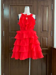 Détails d'une robe licou rouge en mousseline avec volants élégants.