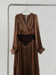Close-up of elegant brown V-neck pleated maxi dress with intricate beaded waist
